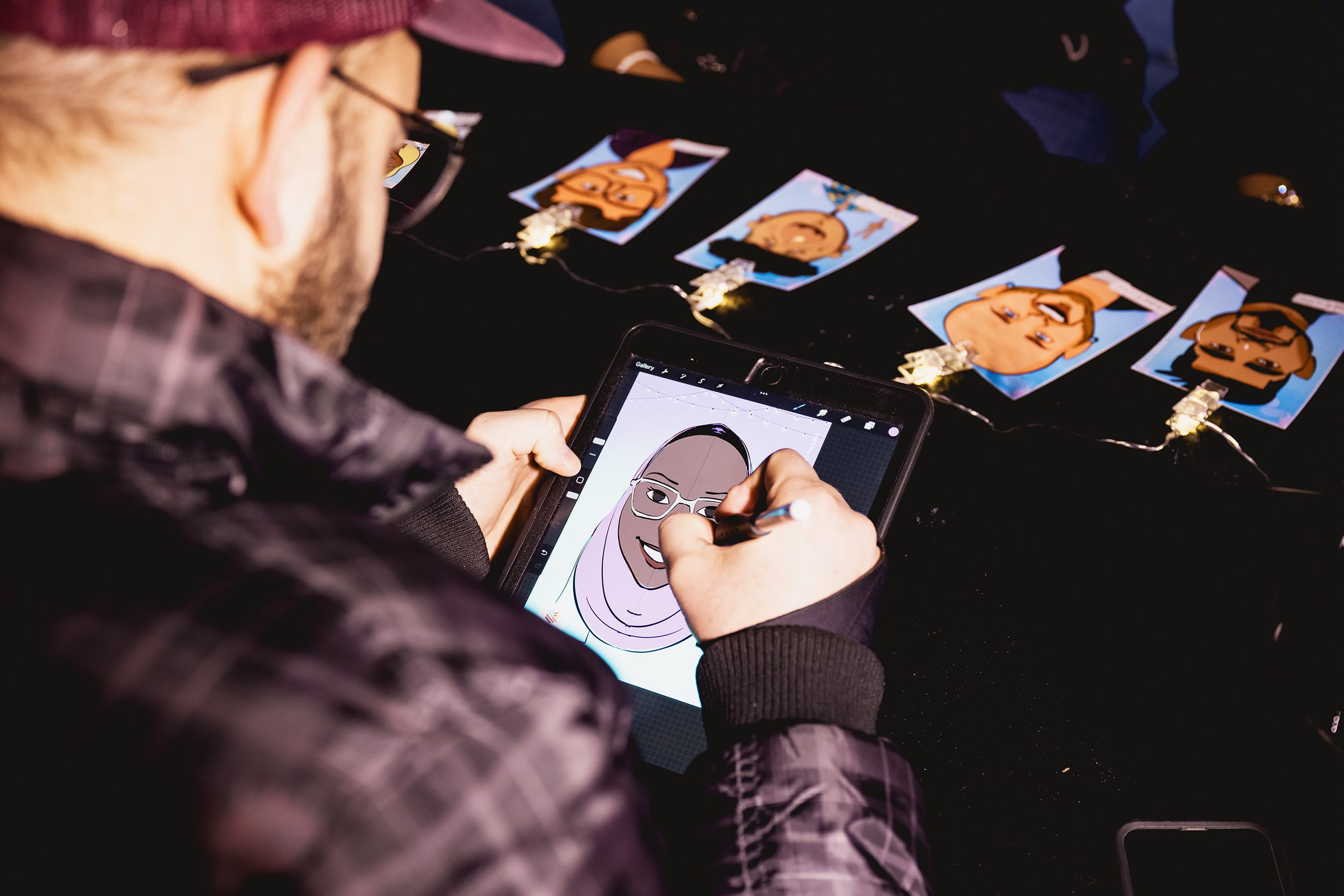 Person drawing on a digital caricatures in Atlanta with images of pumpkins displayed on a dark surface.