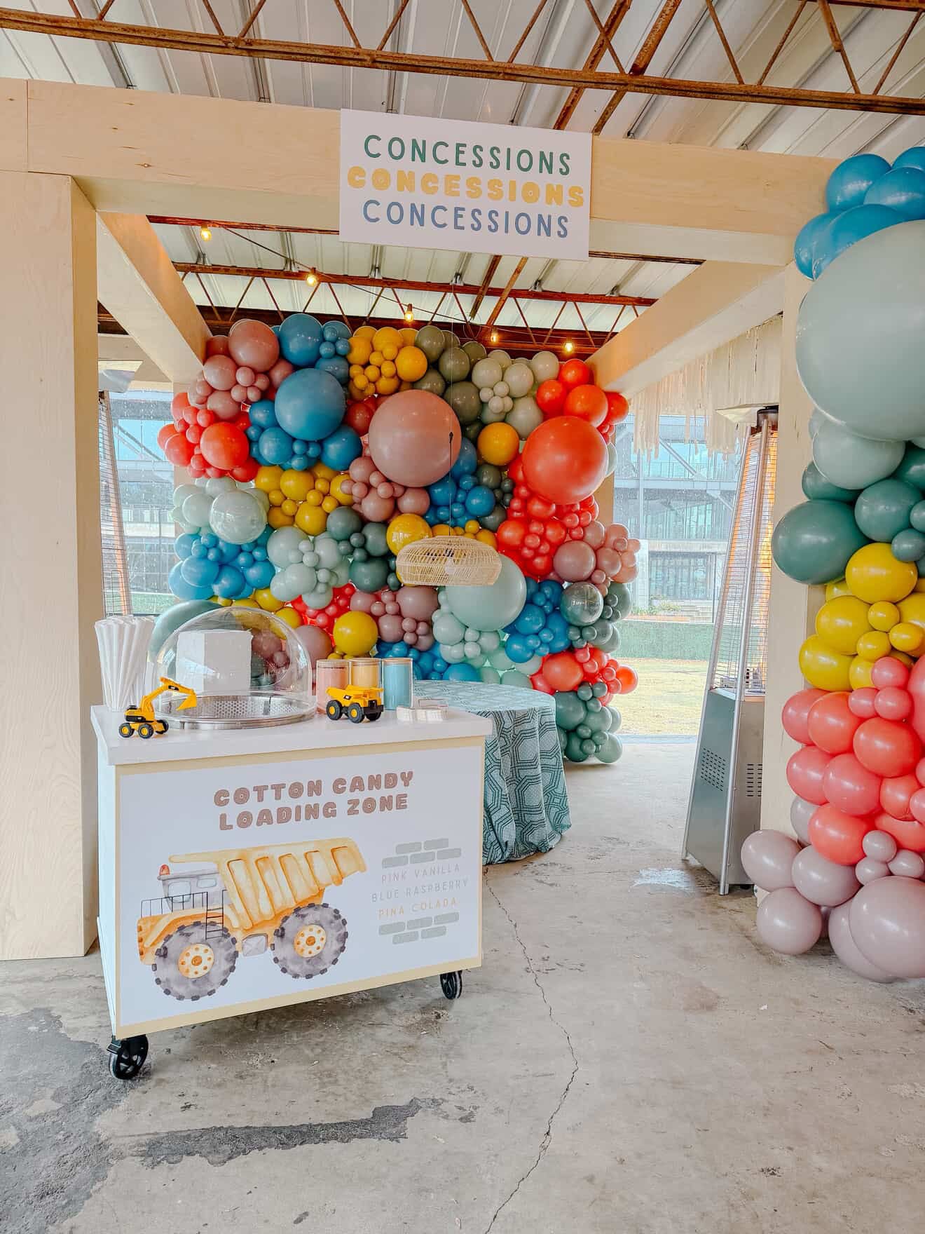 Colorful balloon arch with a cotton candy cart loading zone sign at a birthday party in Atlanta.