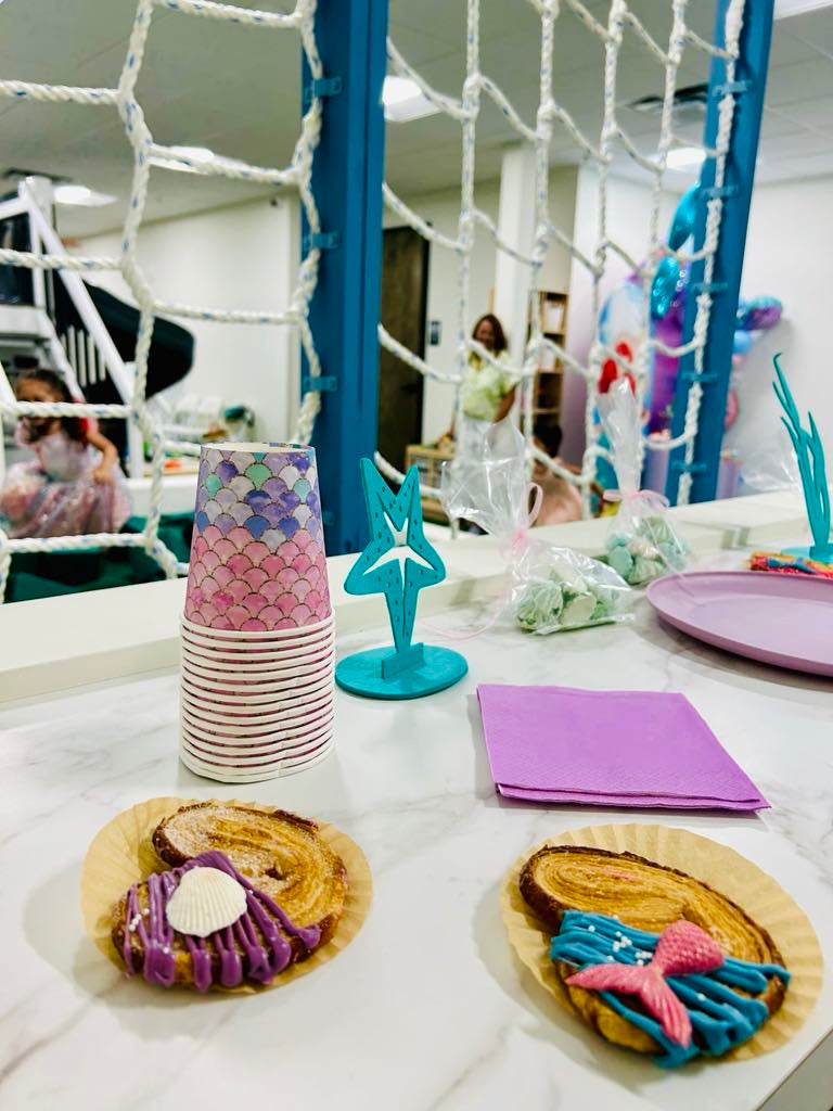 Children's birthday party setup with mermaid-themed plates, napkins, and decorations.