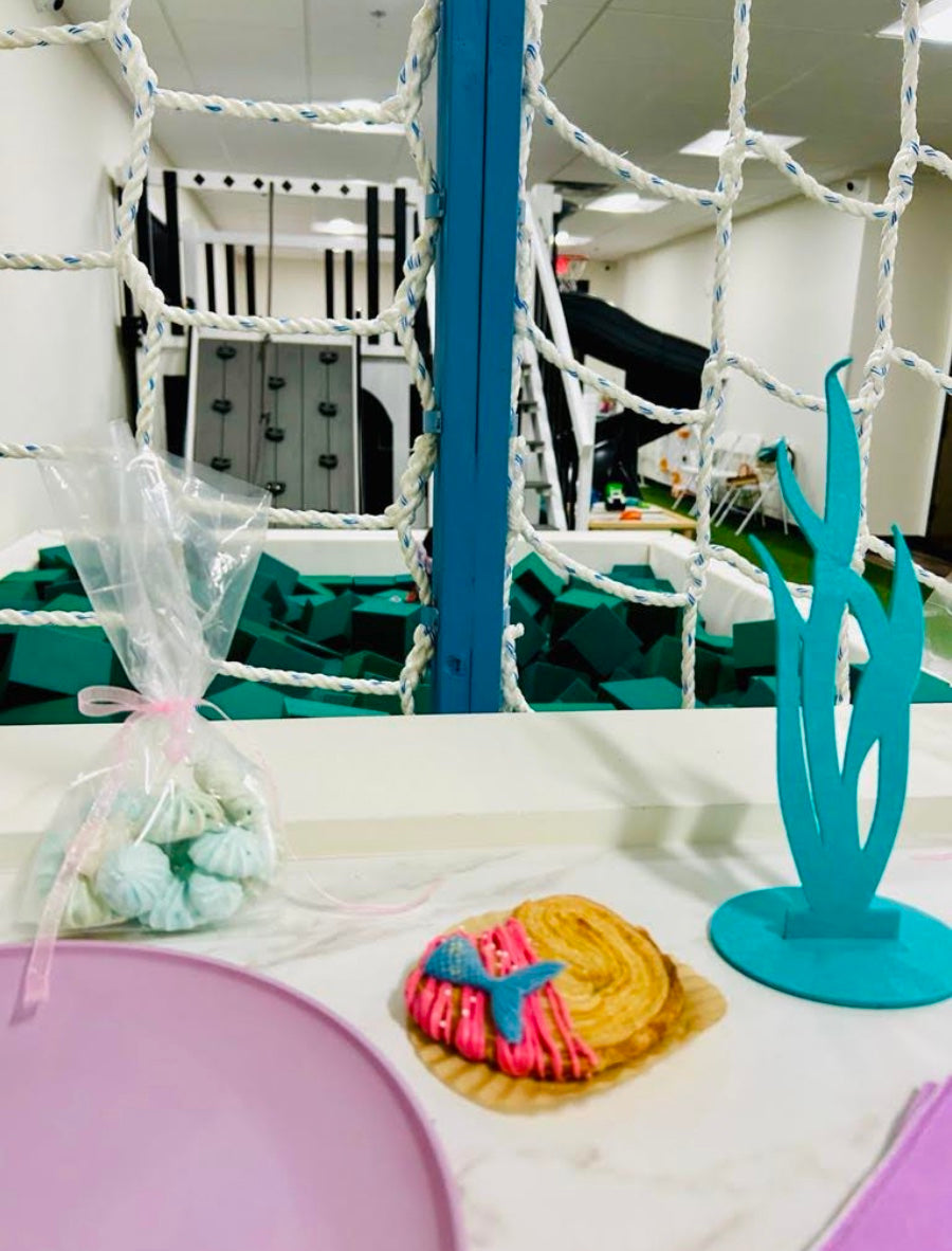 Decorative setup with a blue stand, white netting, and colorful cookies on a table.