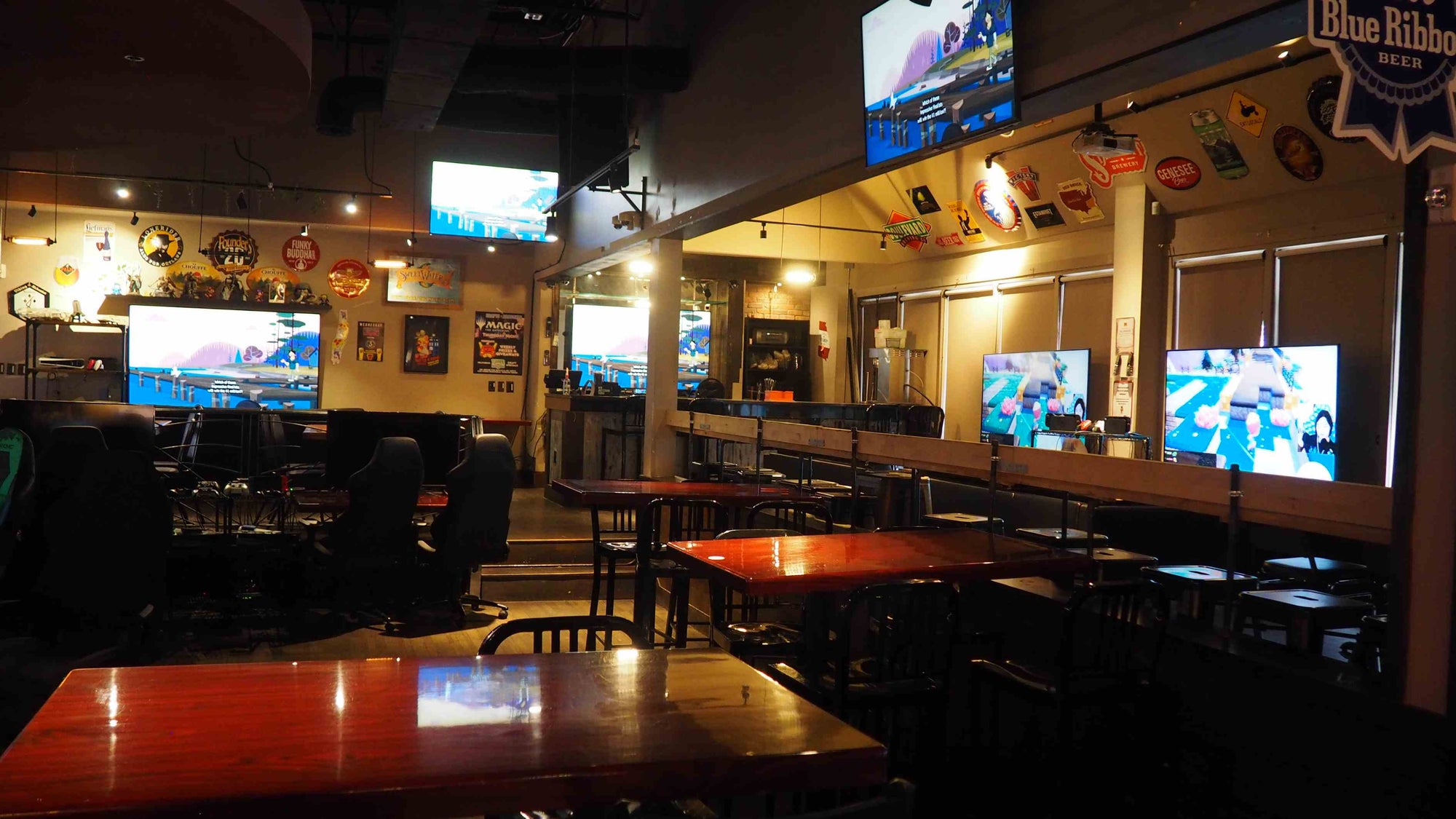 Battle and Brew interior with multiple television screens displaying sports games, wooden tables, and chairs.
