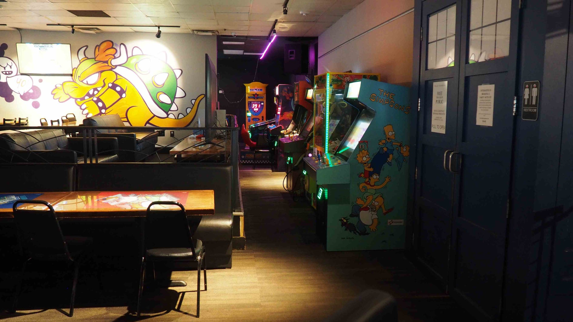 Arcade room with vintage arcade machines and a cartoon character on the wall.
