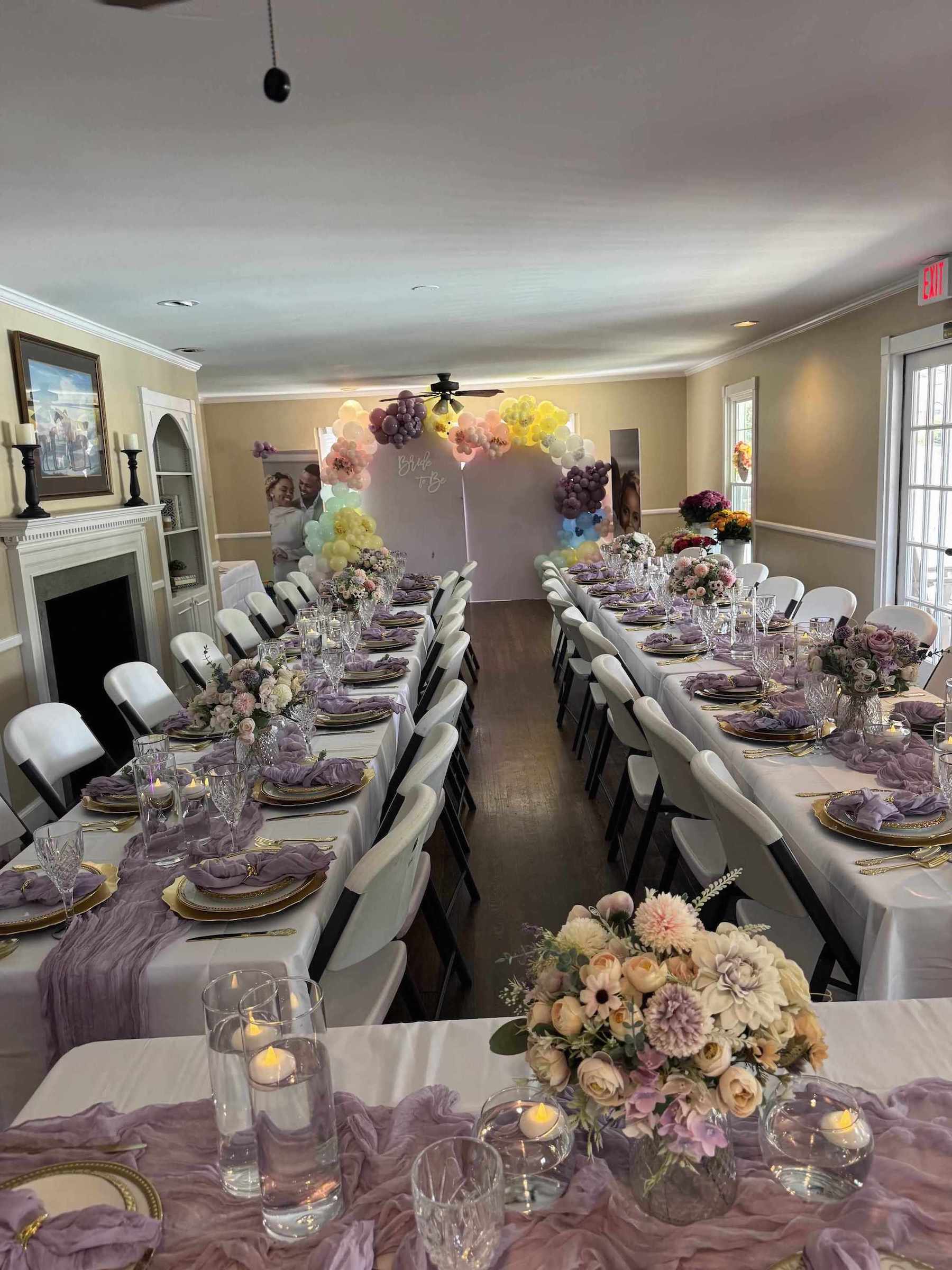 Dining room with tables set for a formal event, featuring floral centerpieces and purple table runners.