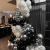 Balloon arch with black, white, and silver balloons in a room setting.