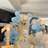 Balloon arch with baby-themed decorations and a 'ONE' sign in a room.
