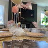 Decorated table with balloons and baby shower programs in a room with a TV in the background for a baby shower in Atlanta.