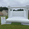 Inflatable white bounce house on grass with a sign in the foreground