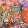 Birthday party setup with balloons, cake, and 'Bluey' themed backdrop.
