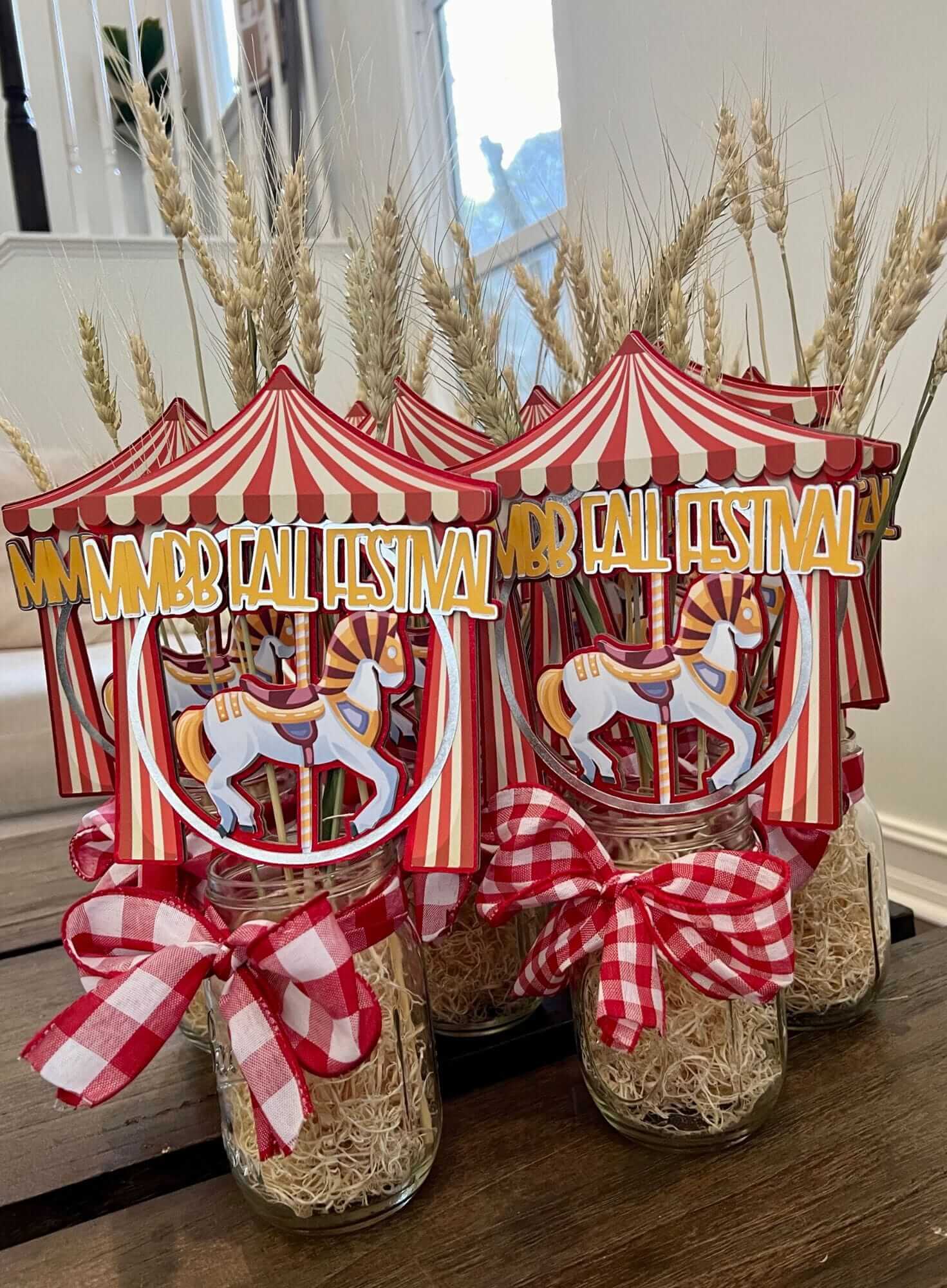 Decorative jars with red and white striped canopies, checkered ribbons, and 'Harvest Festival' text on a wooden surface for a kids birthday party.