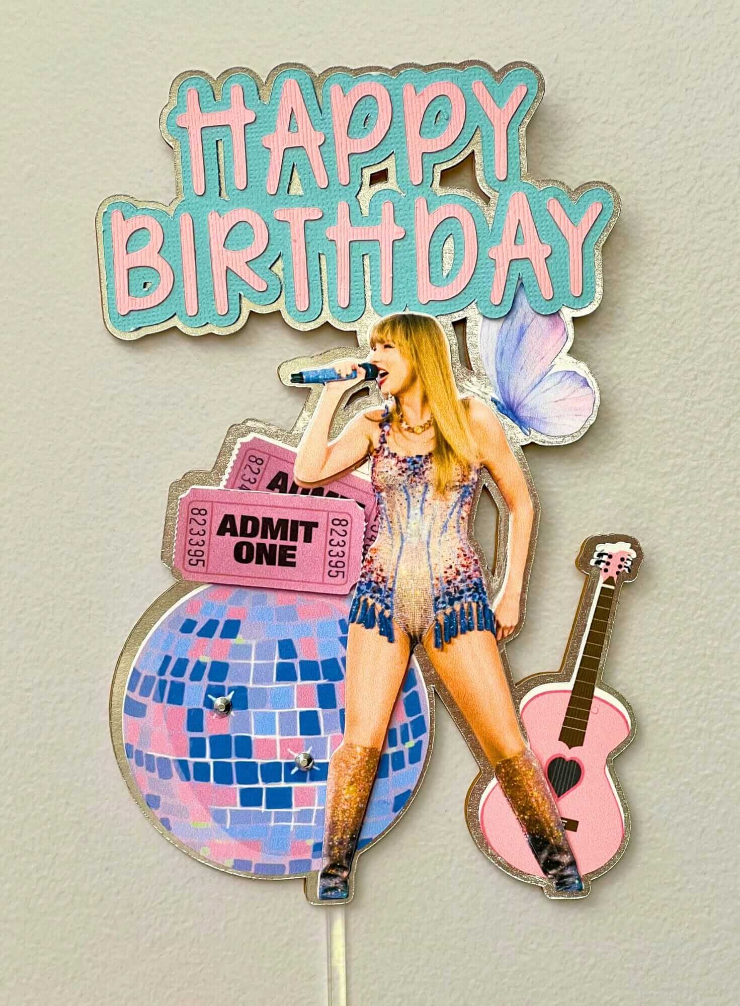 Birthday cake topper with a singer, guitar, and 'Happy Birthday' text on a light gray background.