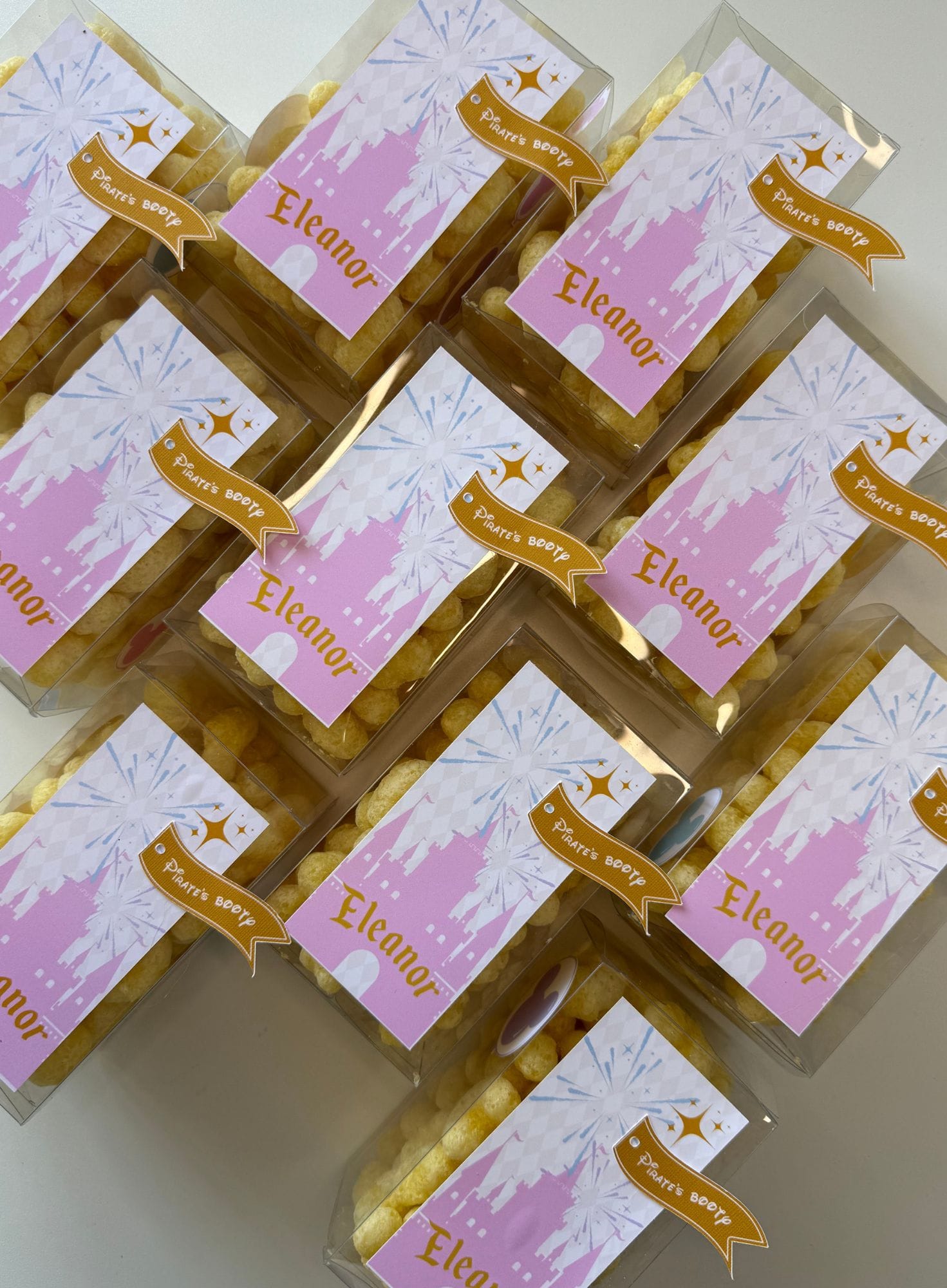Small party favors for a kids birthday party with pink labels and 'Eleanor' text arranged in a grid.