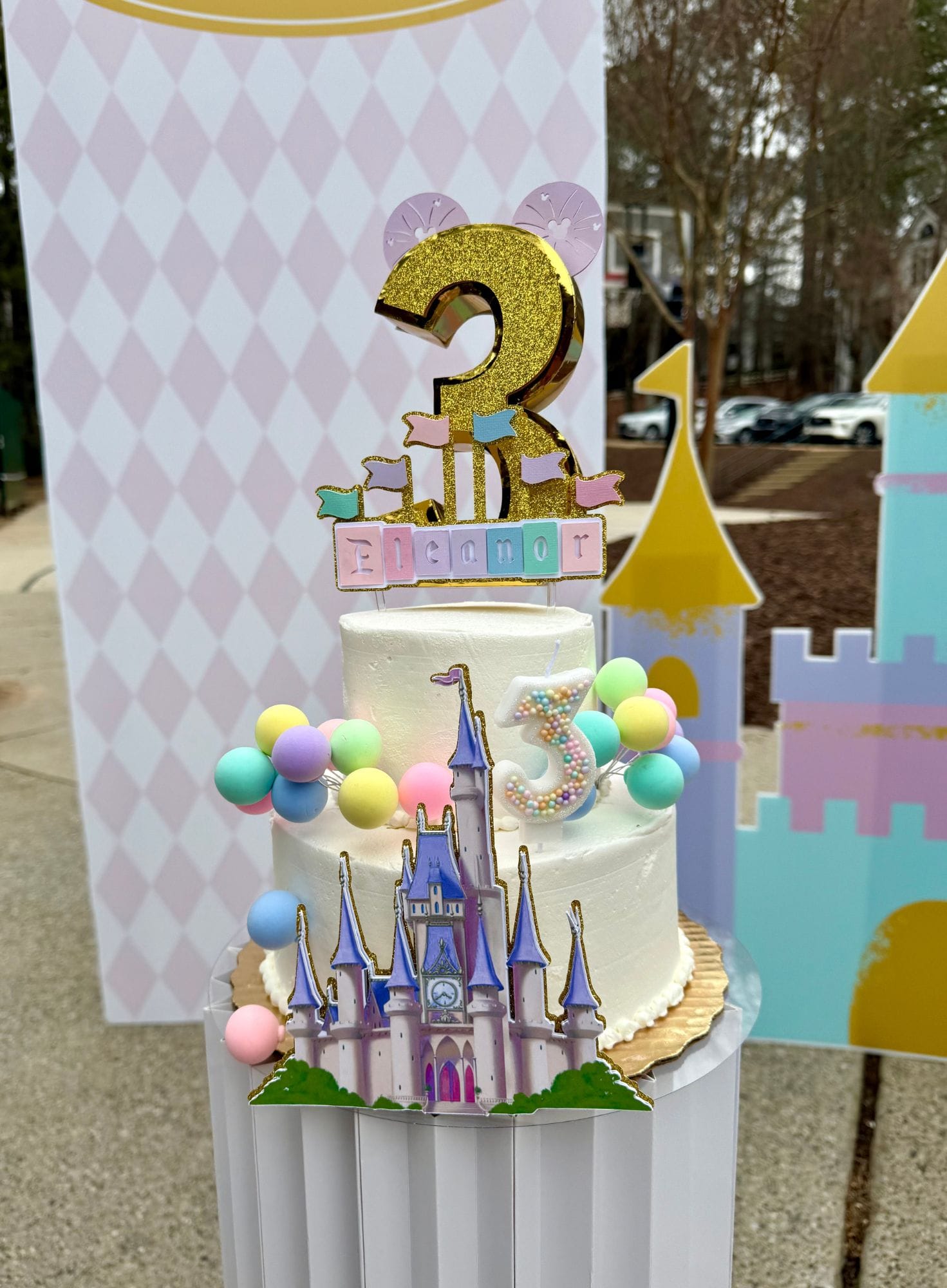 Children's birthday cake with castle design and number 3 topper, outdoor setting for a 3 year old birthday party.