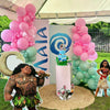 Decorative setup with Moana-themed elements including balloons, a cake, and character cutouts under a tent.