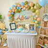 Children's birthday party setup with Winnie the Pooh theme, balloons, and cake.