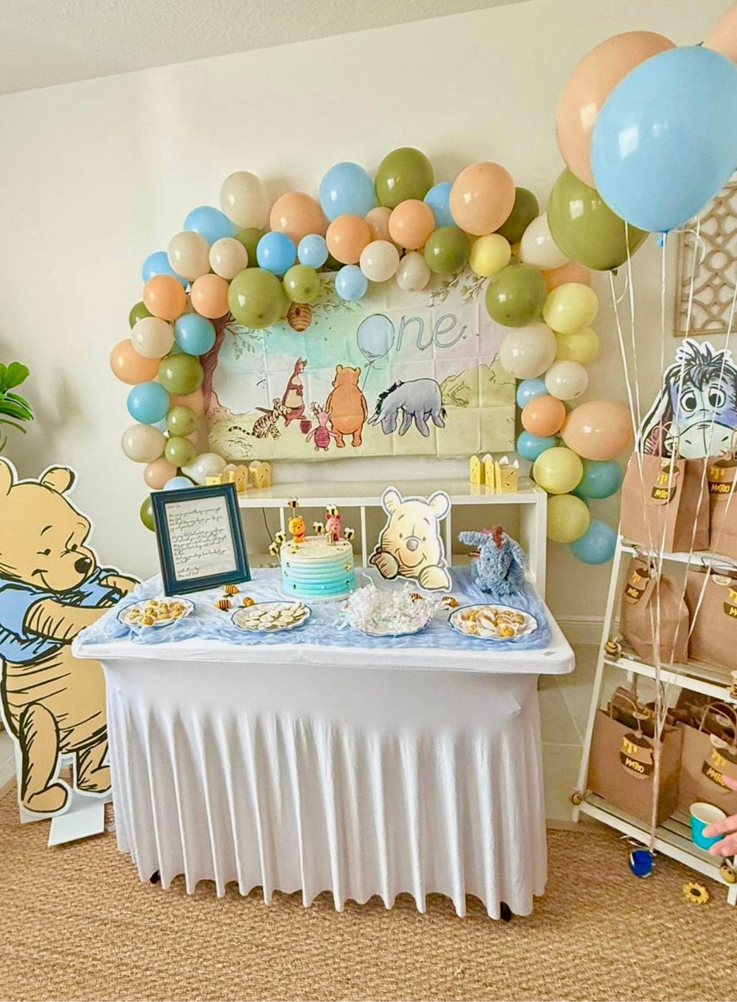 Children's birthday party setup with Winnie the Pooh theme, balloons, and cake.