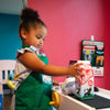 Child playing with a toy cash register in a colorful room at Peachy Pals Playland Cartersville GA | Confetti Jar