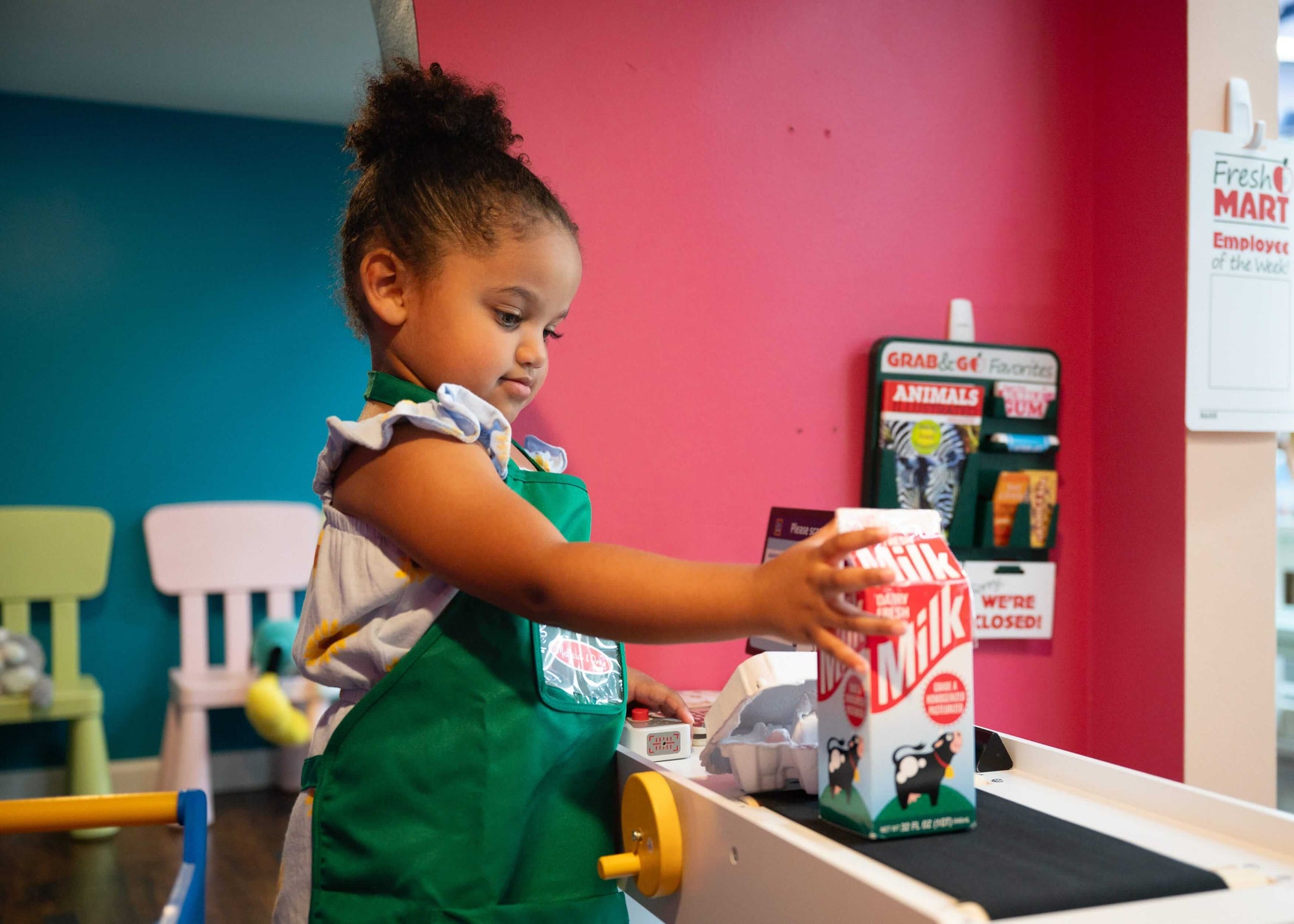 Child playing with a toy cash register in a colorful room at Peachy Pals Playland Cartersville GA | Confetti Jar