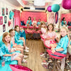 Children in a spa party bus with pink and blue decor, sitting on chairs and couches.
