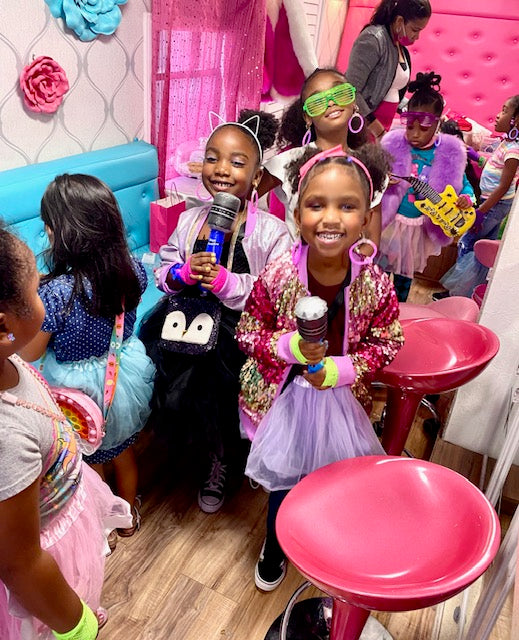 Children in colorful costumes and accessories in a spa party bus in Atlanta.