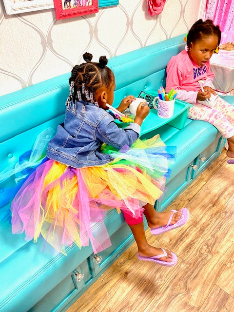 Two young girls playing with toys on a blue play couch in a spa party bus in Atlanta.