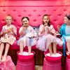 Four girls in colorful dresses sitting on a pink couch with pink buckets filled with bubbles for a girls birthday party in Atlanta.