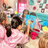 Children in a spa party bus with mirrors, hair products, and decorations.