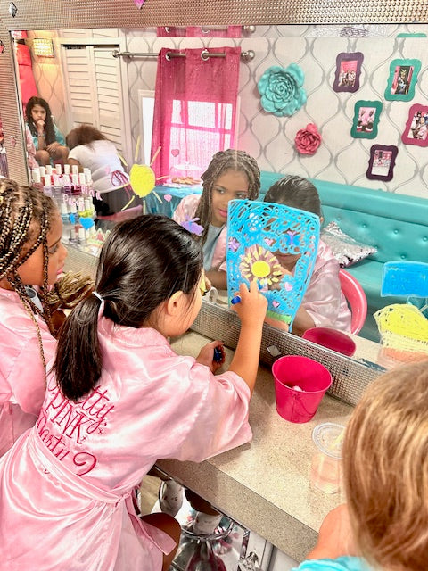Children in a spa party bus with mirrors, hair products, and decorations.