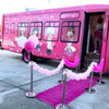 Pink party bus with cartoon characters and a pink carpet leading up to it.