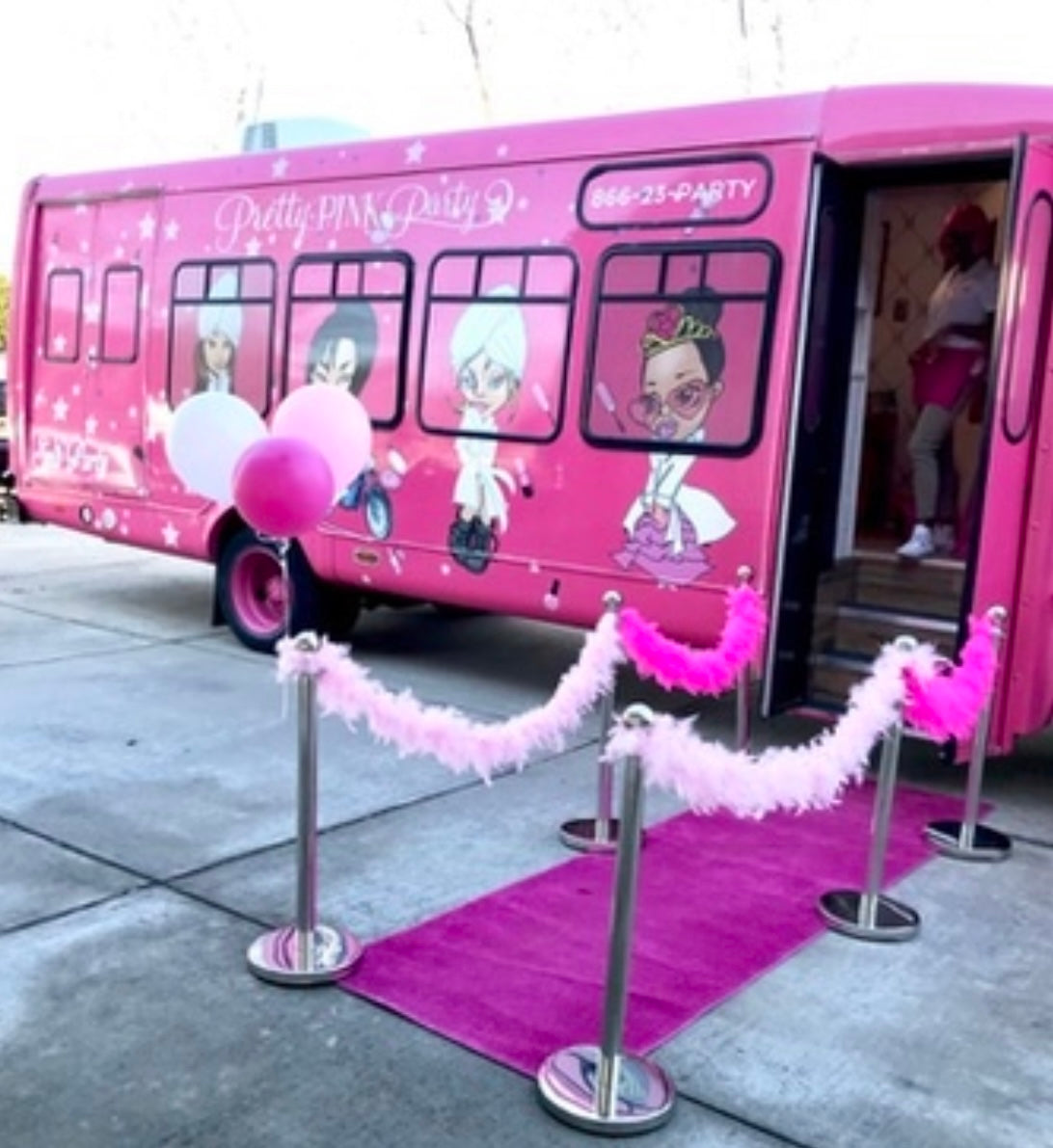 Pink party bus with cartoon characters and a pink carpet leading up to it.