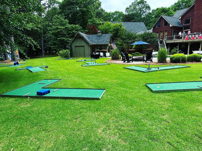 Mobile Miniature golf course set up on a grassy area with buildings and trees in the background. for a teen birthday party | Confetti Jar