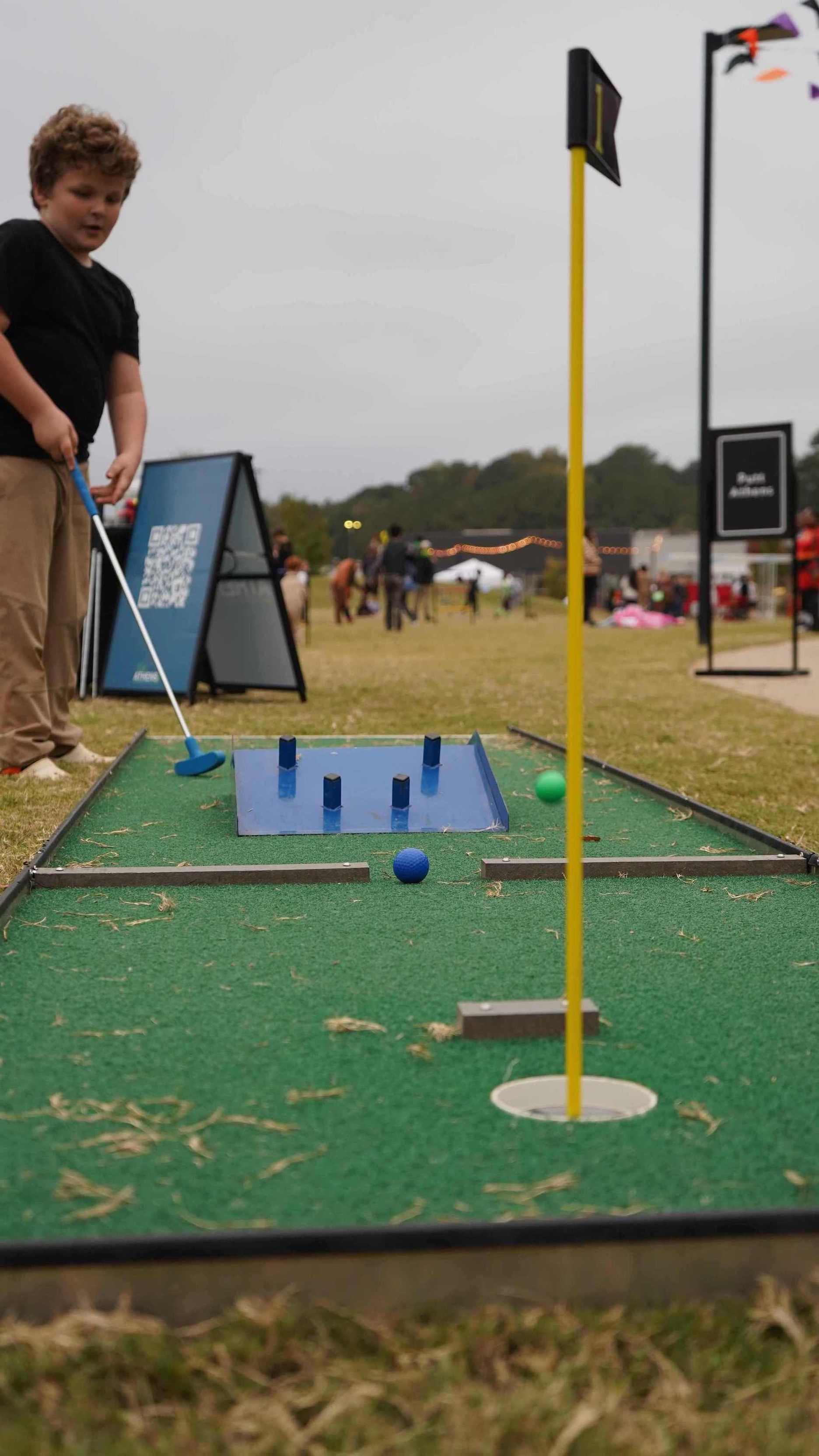 Child playing mini golf on a course with a green background for a community event in Atlanta GA | Confetti Jar