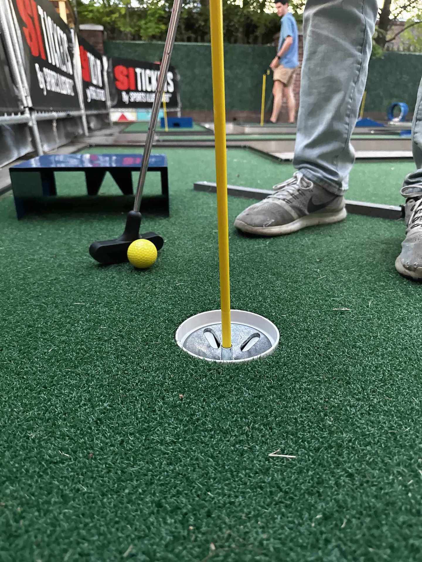 Mobile putt putt golf scene with a yellow ball and club on a green putting surface at a party in Atlanta GA | Confetti Jar