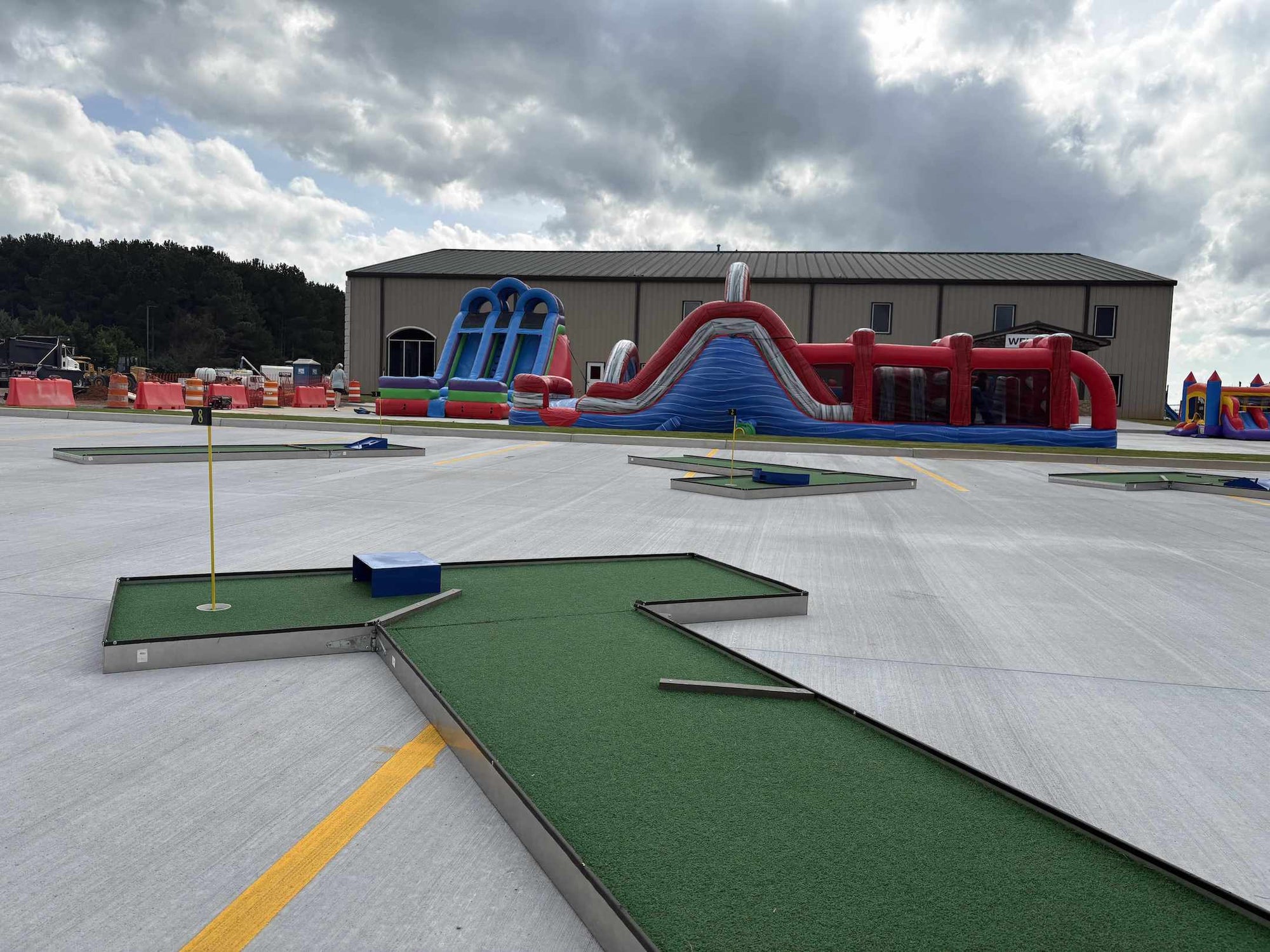 Mobile putt putt golf course with inflatable slides in the background for a party | Confetti Jar