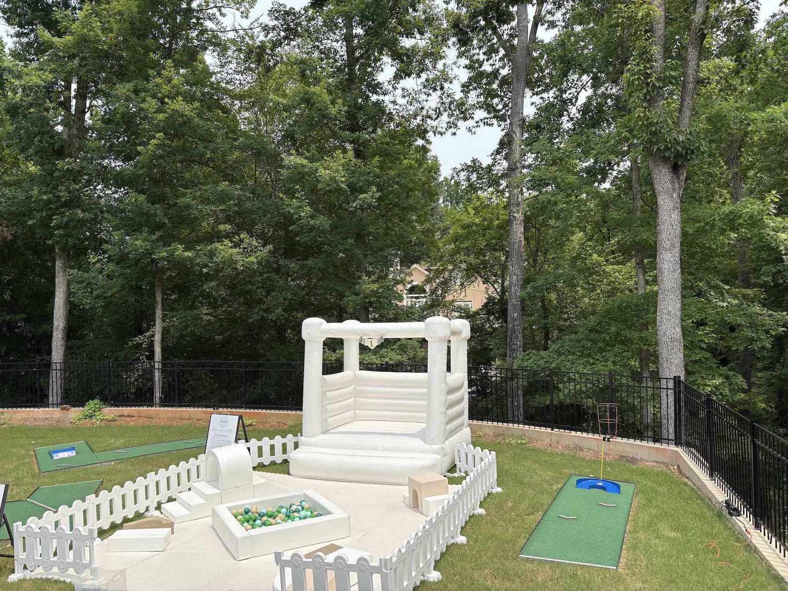 Backyard with inflatable obstacle course and mobile mini golf setup | Confetti Jar