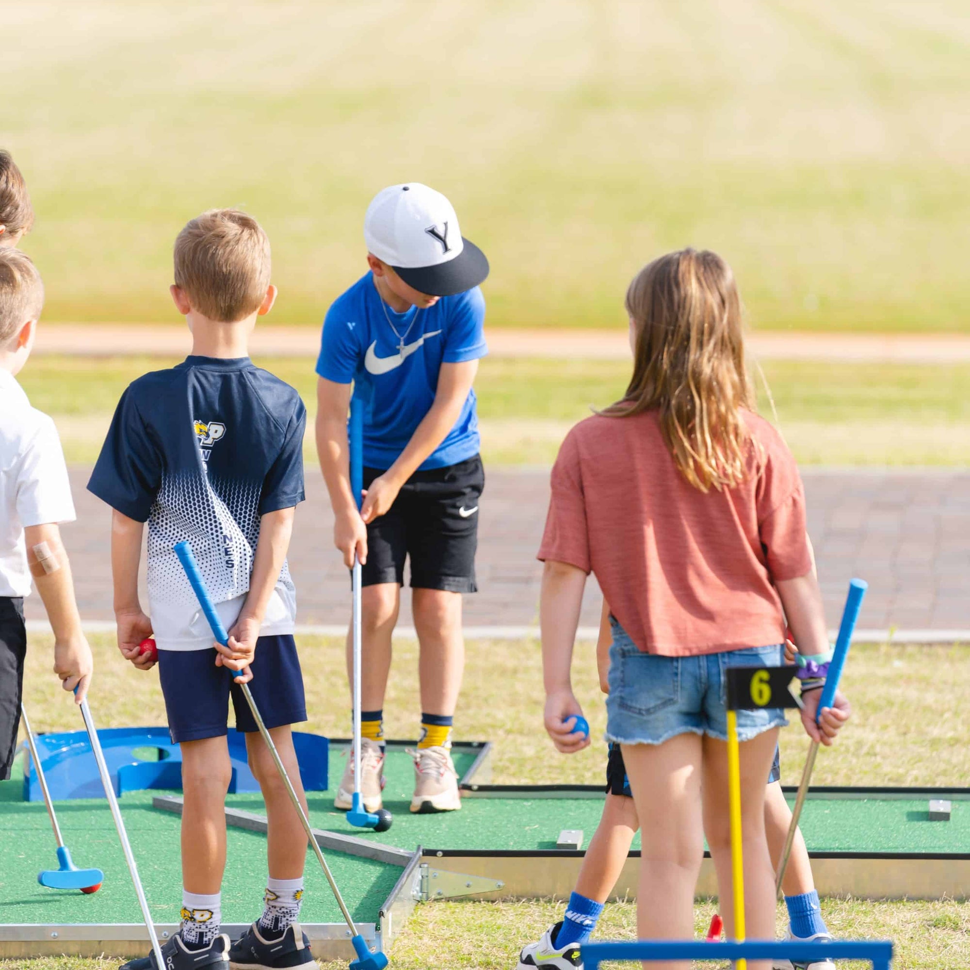 Children playing mini golf on a sunny day for a kids golf birthday party in Atlanta | Confetti Jar