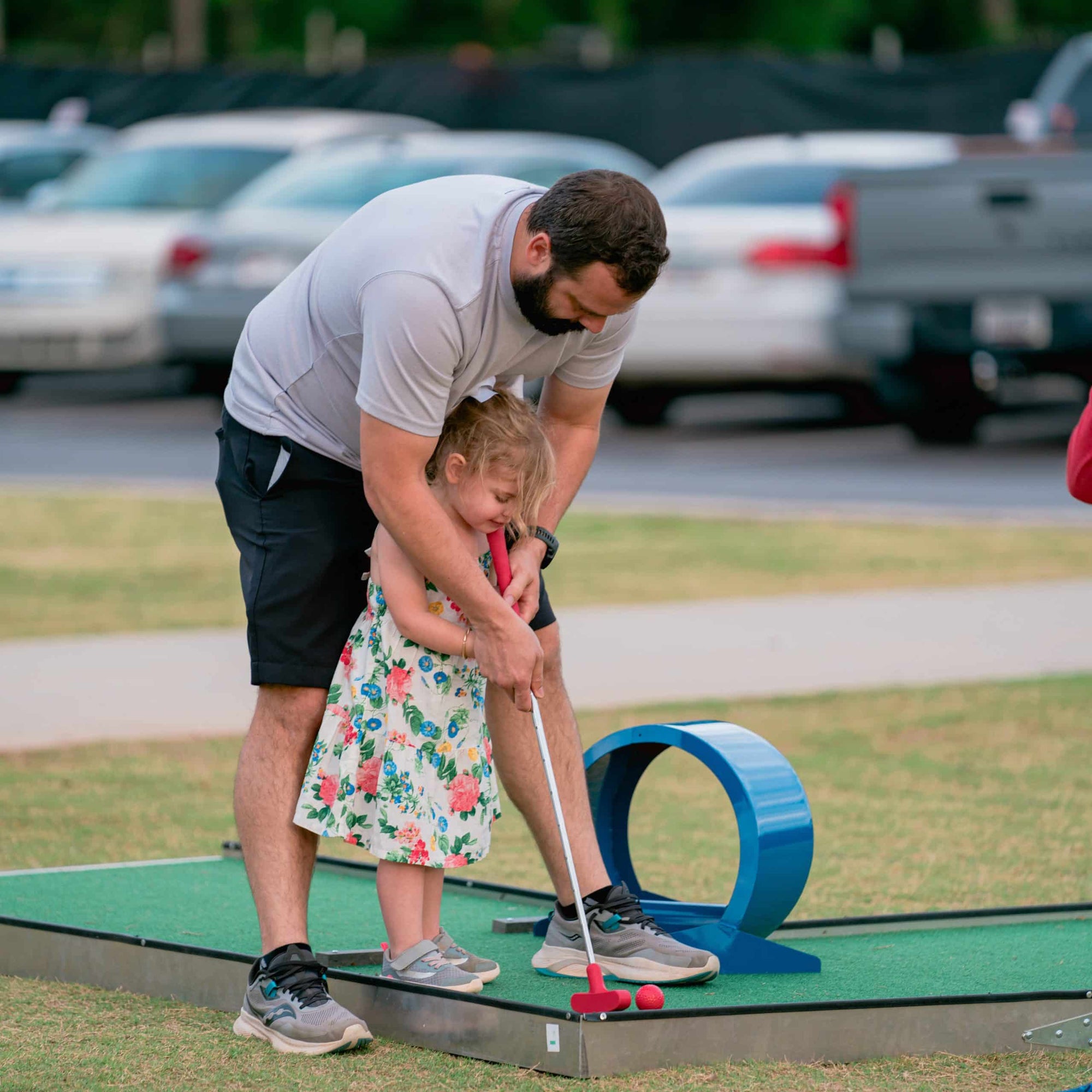 Man and child playing mini golf on a mobile putt putt course in Atlanta for a birthday party | Confetti Jar