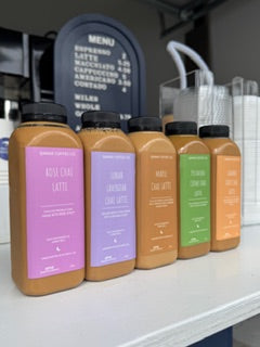 Row of coffee drinks in bottles with colorful labels on a shelf.