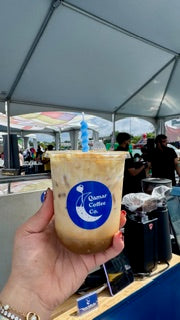 Person holding a cup with a visible brand logo at an outdoor event.