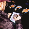 Person drawing on a digital caricatures  in Atlanta with images of pumpkins displayed on a dark surface.