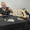 Man sitting at a table with a 'HEY' light-up sign and other items.