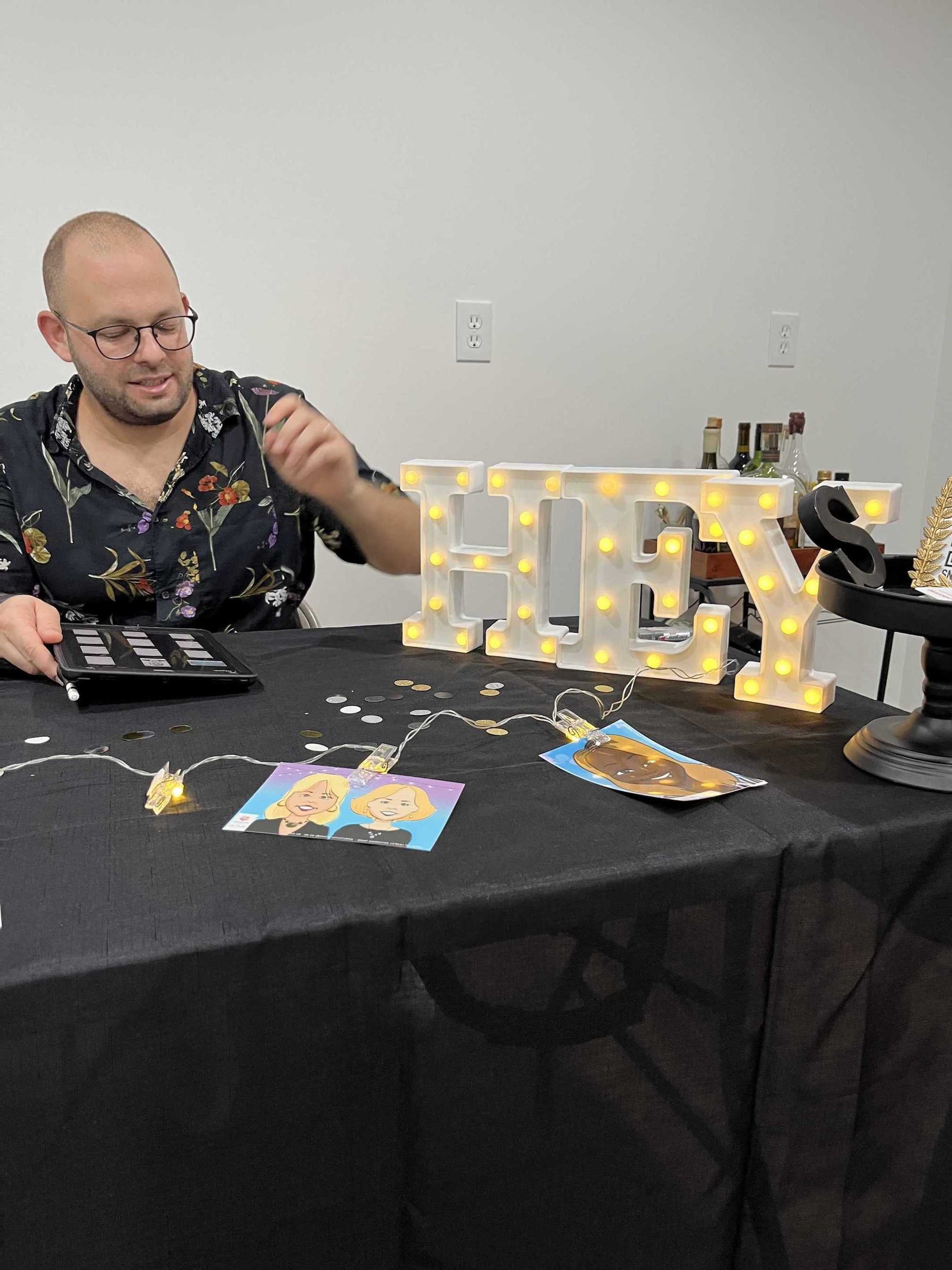 Man sitting at a table with a 'HEY' light-up sign and other items.