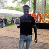 Man holding a digital caricature  in Atlanta at an outdoor event with trees and tents in the background.