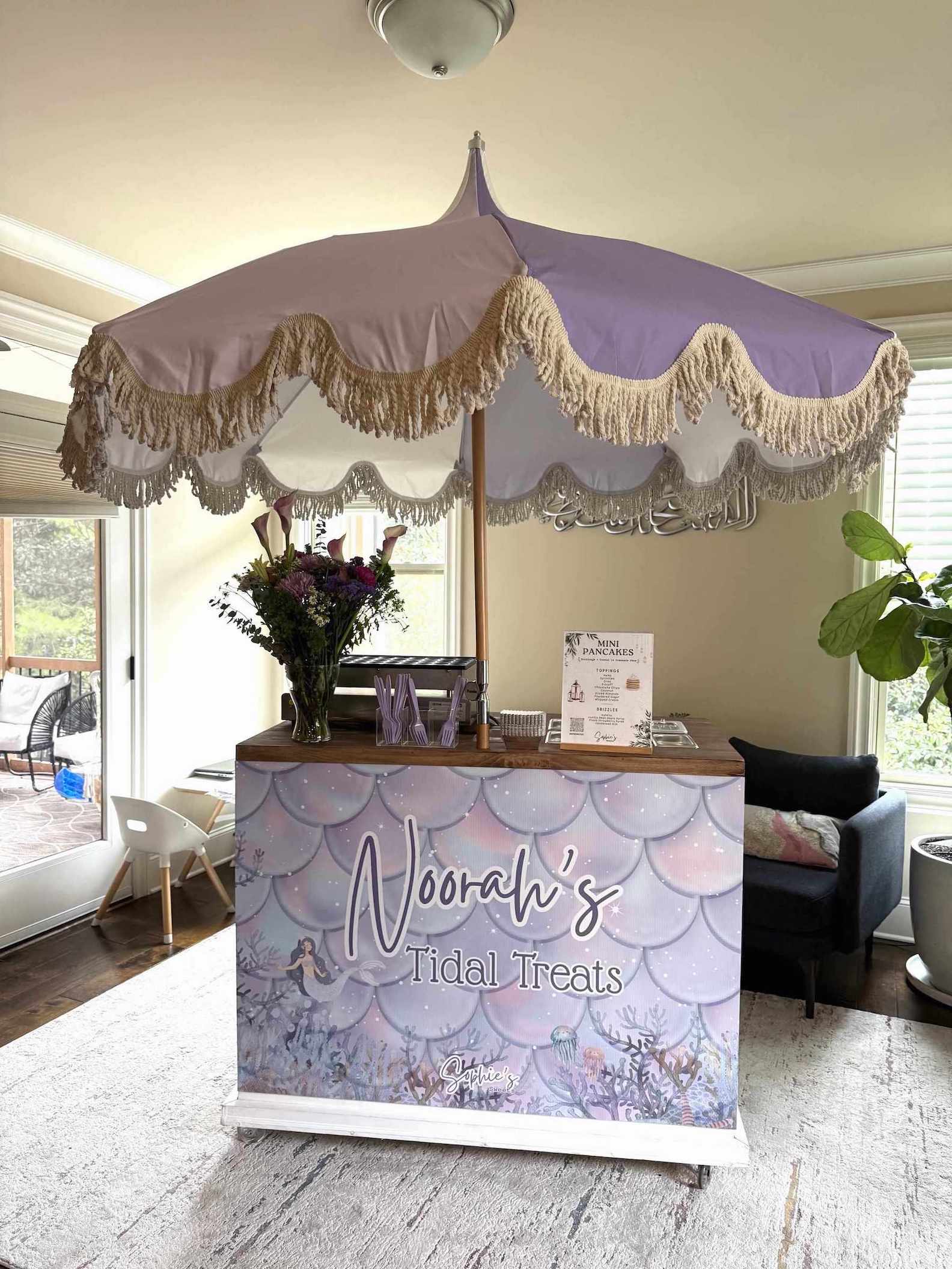 Umbrella with decorative fringe over a branded counter in a room with furniture and decor | Dessert Cart Atlanta | Confetti Jar