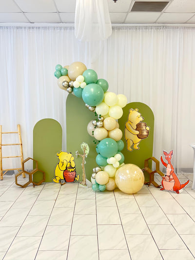 Balloon arch with Winnie the Pooh and friends decorations in a room.