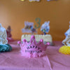 Pink birthday crown on a table with a blurred background of a birthday cake and decorations for a girls birthday party in Johns Creek GA.