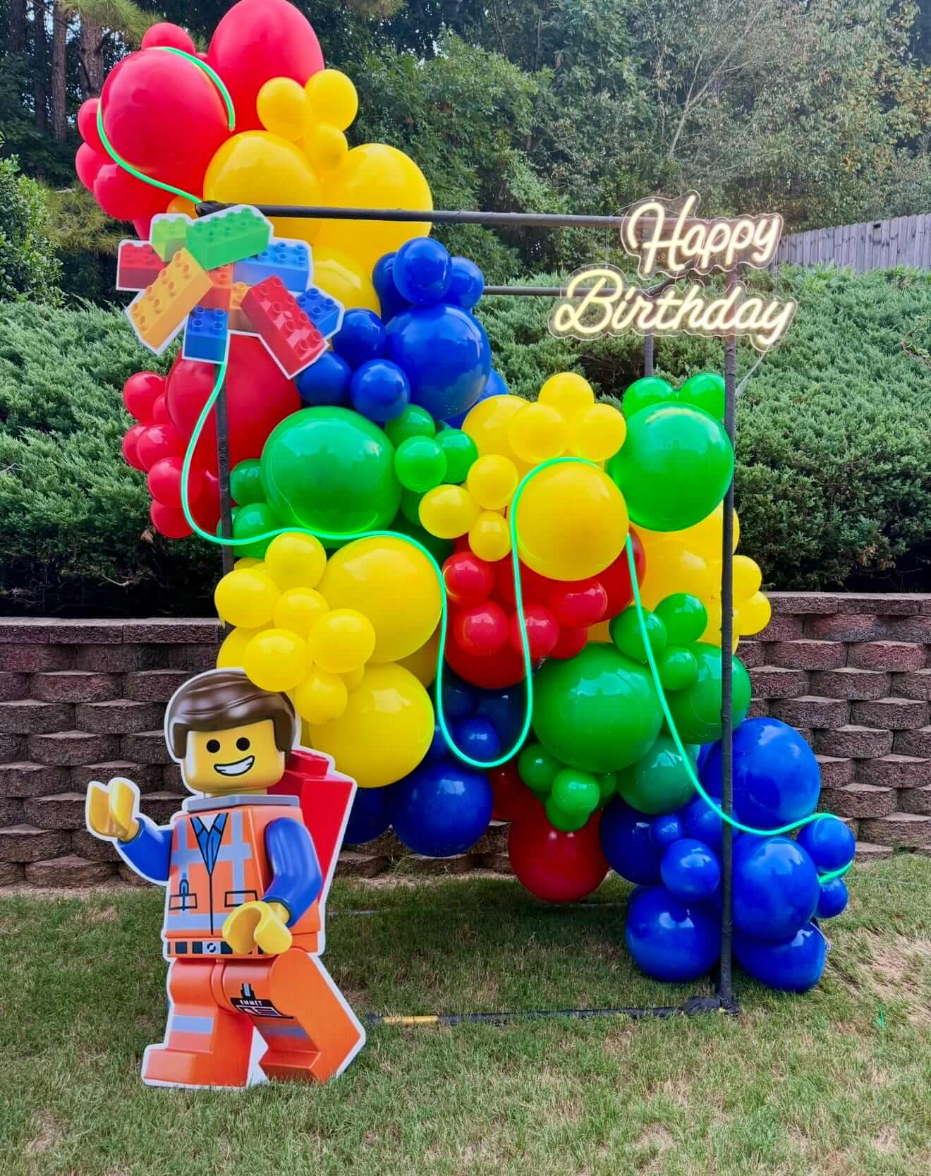 Colorful balloon arch with a 'Happy Birthday' sign and a Lego figure in the foreground