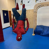 Person in Spider-Man costume hanging upside down in a room with blue floor and beige walls at and indoor birthday party for kids in Atlanta | Confetti Jar