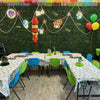 Children's party setup with tables, chairs, balloons, and decorations against a green wall at an indoor birthday party for kids in Atlanta | Confetti Jar
