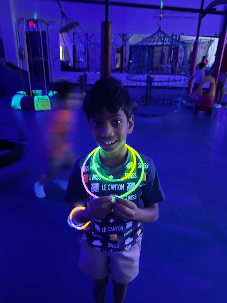 Child wearing a glowing necklace in a dark indoor setting at a birthday party for kids in Atlanta | Confetti Jar